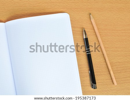 Blank notepad with pen and pencil on office wooden table