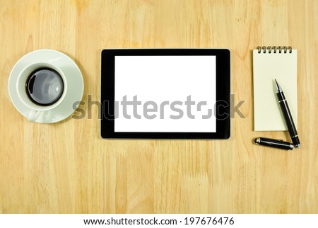 Digital tablet computer with sticky note paper and cup of coffee on wooden desk.