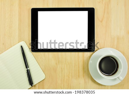 Digital tablet computer with note paper and cup of coffee on  wooden desk.