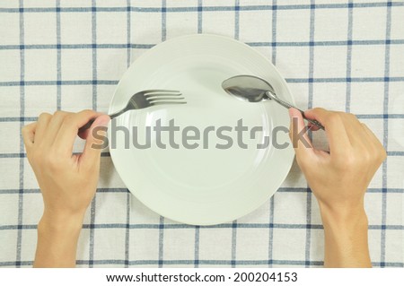 Man sitting at the dinner table with fork  and spoon and empty plate