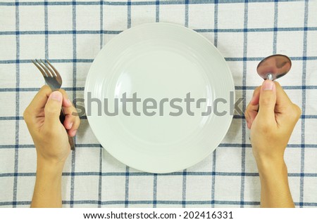 Man sitting at the dinner table with fork and spoon and empty plate