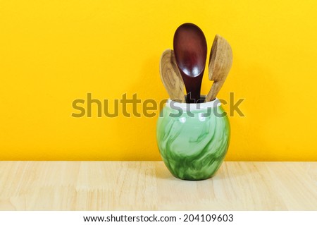 Kitchen Decor: spoon in ceramics container on a wooden board background , cozy arrangement retro style, yellow wall.
