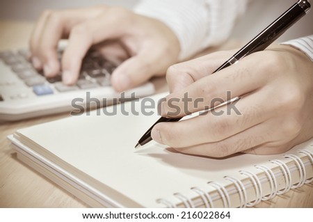 Businessman writing report and calculate on the desk in office.
