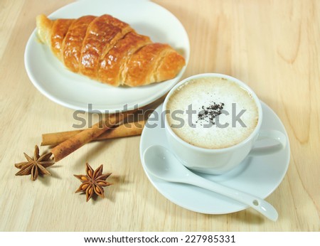 hot Cappuccino  and Croissant with cinnamon ,anise on wood table