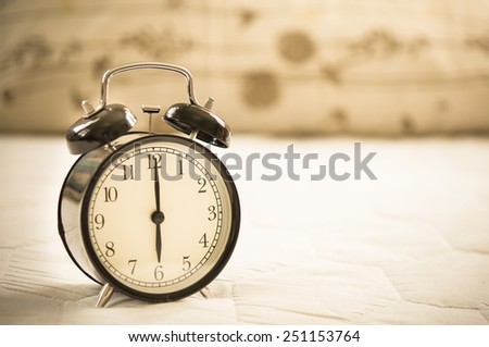 Vintage alarm clock on bed.