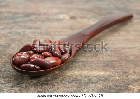 red beans in wood spoon on wood table.