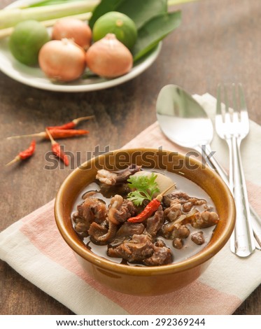 Thai beef curry in brown bowl on wood table.