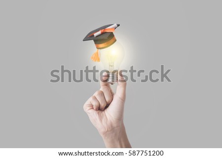 student hand holding light bulb with graduation hat on gray background. concept education of new ideas with innovation and creativity.