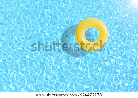 yellow swimming pool ring float in blue water. concept color summer.