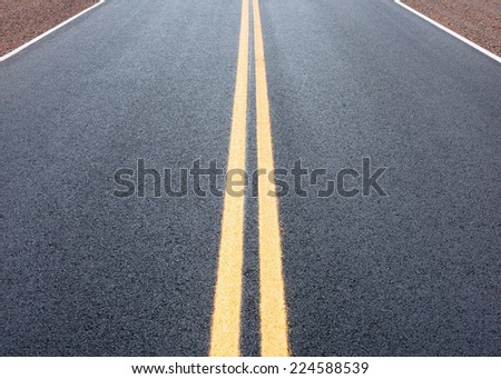 Detail view of highway pavement with yellow double line.