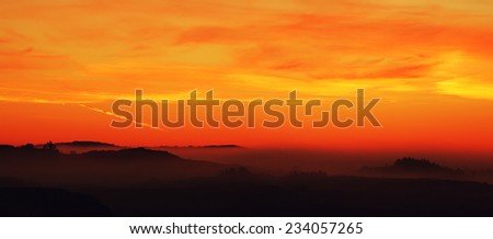 Silhouetted landscape panorama with warm sky at daybreak