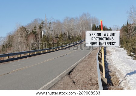 Spring weight restriction sign beside rural highway on sunny day.