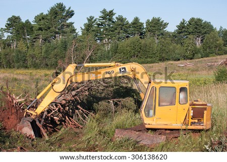 WENTWORTH, CANADA - AUGUST 11, 2015: John Deere excavator in rugged outdoor area. John Deere is an American company manufacturing heavy industrial and lawn care equipment.