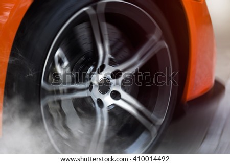 Orange Sport Car with detail on spinning and smoking wheels/tires doing burnouts, dynamic photo