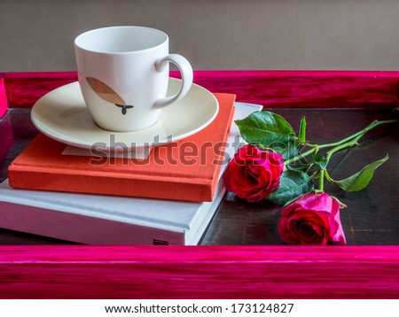 Cup of coffee with a books & red roses in rustic pink tray