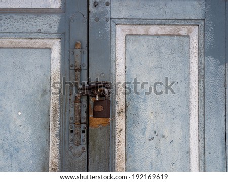 Asian ruin blue door locked with a rusty Padlock and latch