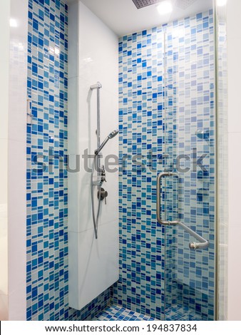 Abstract blue glass mosaic with shower faucet in bathroom