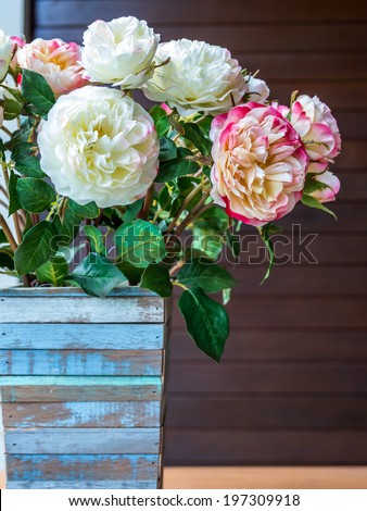 Artificial roses with rustic wooden vase in modern interior room