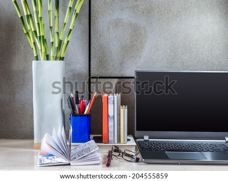 Modern home office desk with laptop, lamp and vase of flowers