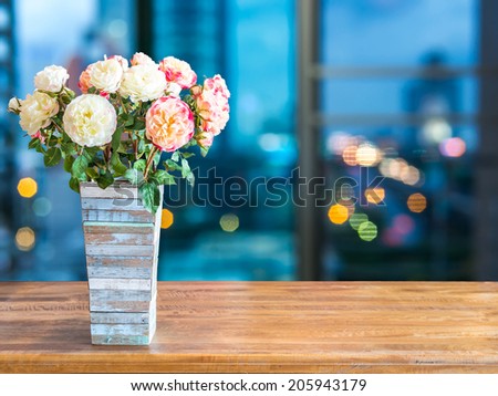 Flower vase on rustic tabletop with abstract blurred modern cityscape night background