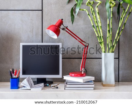 Modern office desk with computer, lamp and vase of Lucky bamboo
