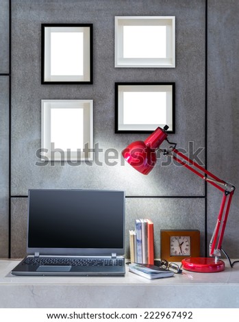 Modern office desk decorated with laptop, lamp and blank  picture frames
