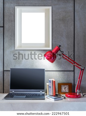 Modern office desk decorated with laptop, lamp and blank  picture frame