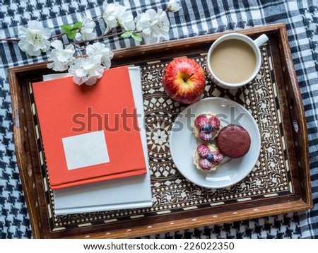 Still-life of books, tea cup, appetizer in vintage wooden tray