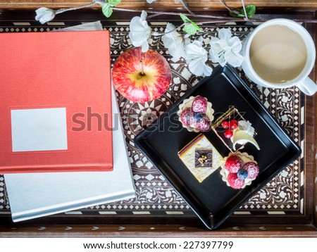 Still-life of books, tea cup, appetizer in vintage wooden tray