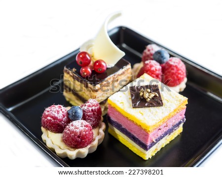 Slice of delicious  layer mousse cake and raspberries fruit tart