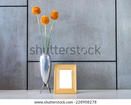 Modern interior wall with vase of flowers and blank picture frame