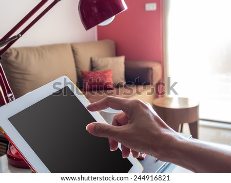 Hand touching tablet with blank screen in modern office background