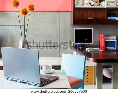 Modern workplace with laptop computer and vase of flower on desktop