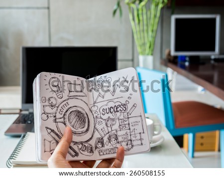 Hand holding sketch book of success key over modern workspace background