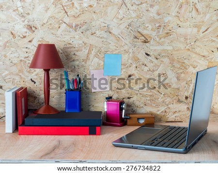 Modern creative workspace with laptop computer / compressed plywood chipboard wall background