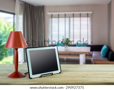 Red lamp, tablet on wooden table top with modern  Dining room blurry background