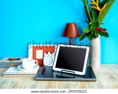 Still life of modern colorful interior workspace with laptop, tablet, flower vase