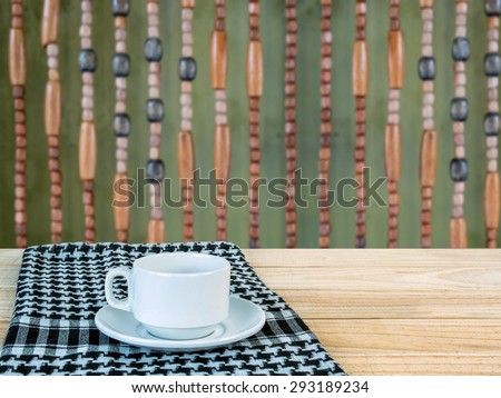 White coffee cup on wooden tabletop over  hanging wooden beads  background