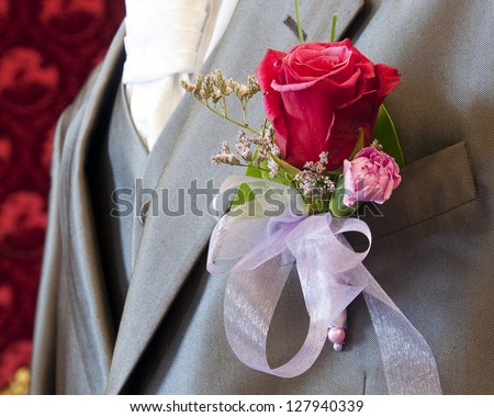 Wedding button flower, rose and carnation, in a lapel of groom suit.
