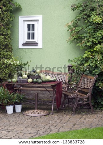 Small patio or street garden with rustic chair and table, green vegetable and plants.