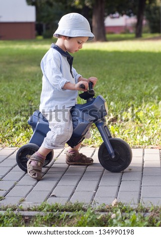 A small boy learning to ride his first plastic toy bike.