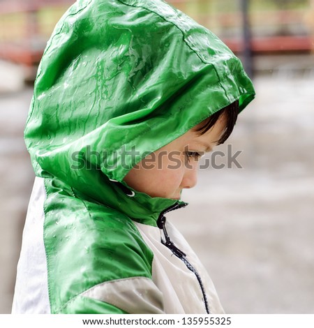 Child in waterproof jacket in the rain, profile portrait.