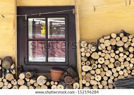 Wooden window of a traditional country cottage house with firewood logs.