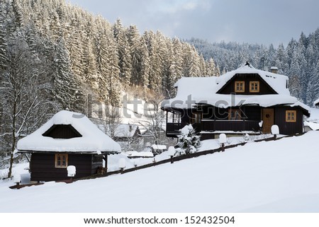 Wooden cottage holiday house in mountain holiday resort covered with fresh snow in winter.
