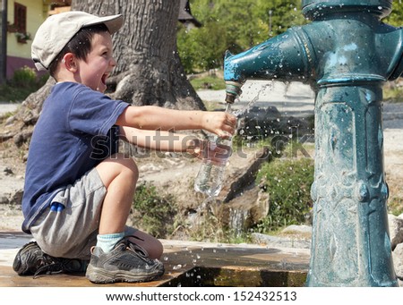 Child filling water bottle from a hydrant fountain.