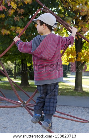 Child playing at playground on a rope climbing frame.