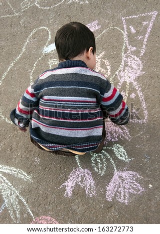 Child chalk drawing on the pavement outside.