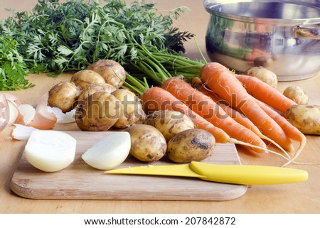 Raw carrot, new potatoes and onion vegetable on a table ready for soup.