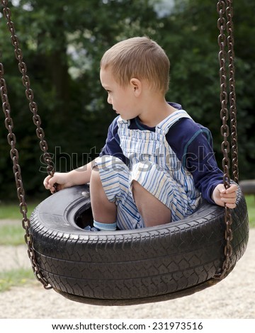 Child playing on tire swing at children  playground park.