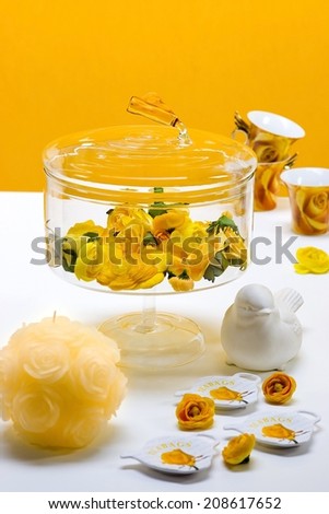 yellow roses in  bell jar, candle and ceramic bird for party